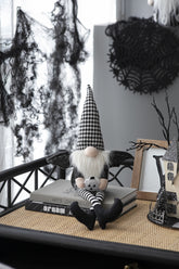 Halloween-themed decor with a gnome, books, and decorative items on a table.