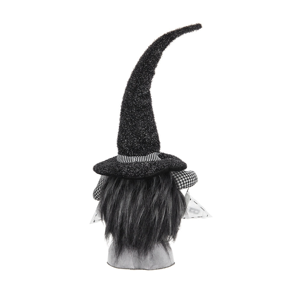 A black witch-themed decorative gnome head with a tall curved pointed hat, black faux hair, a checkered band, and small white wings, shown on a white background.