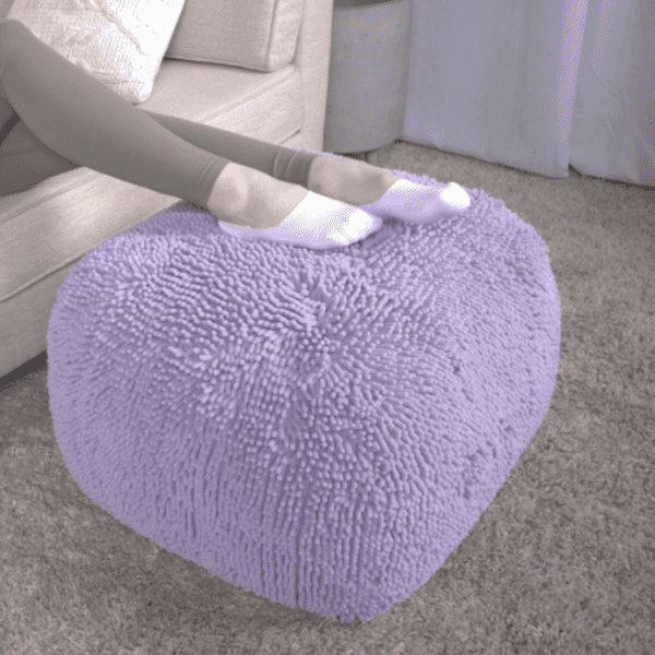 Person sitting on a fluffy purple ottoman in a living room.