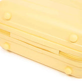 Bottom view of yellow ABS spinner luggage with rounded feet and durable exterior, showcasing its compact and lightweight design.