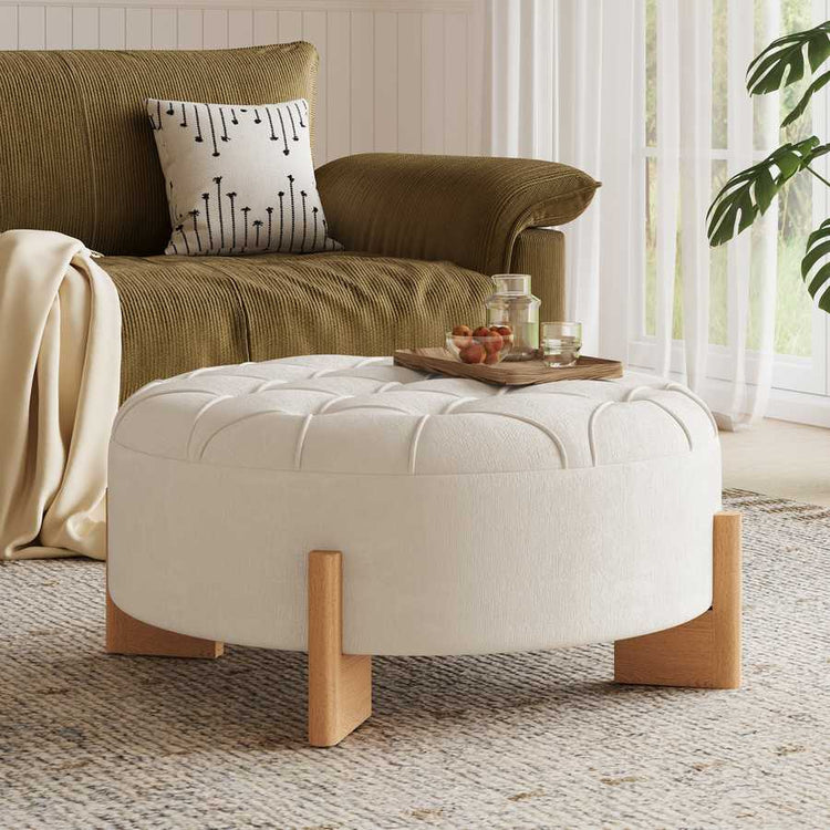 Brown sofa with a patterned pillow and white ottoman in a living room setting.