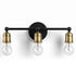 Three-light wall sconce with black and brass finish on a white background