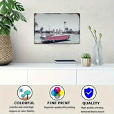 A framed wall art print showing a vintage red car on a city street, displayed above a white console table with a plant, books, and a vase. Three circular icons at the bottom highlight colorful print, fine print quality, and overall quality.