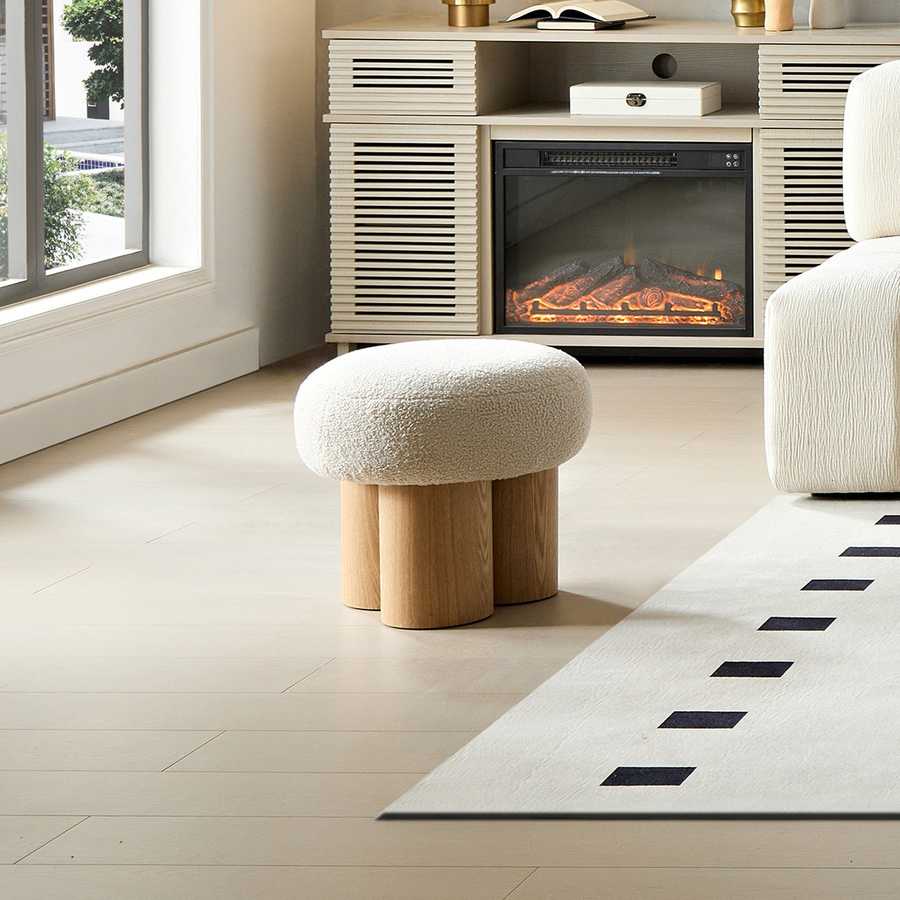 Modern living room with a textured ottoman, fireplace, and rug.