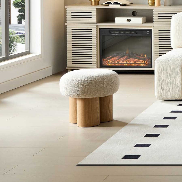 Modern living room with a textured ottoman, fireplace, and rug.