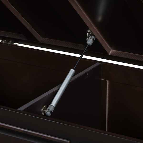 A close-up of a dark brown wooden storage cabinet with its lid open, supported by a silver metal hydraulic gas lift rod.