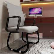 Modern office chair with black frame and white cushion in a room with a computer monitor on a desk.