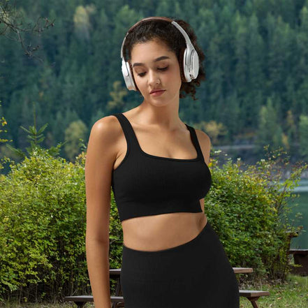 Woman wearing headphones and a black sports outfit in a natural setting