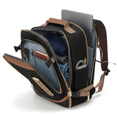 A black and brown backpack shown open, revealing its interior compartments, with a laptop, folded blue clothing, and other accessories inside, photographed on a clean white background.