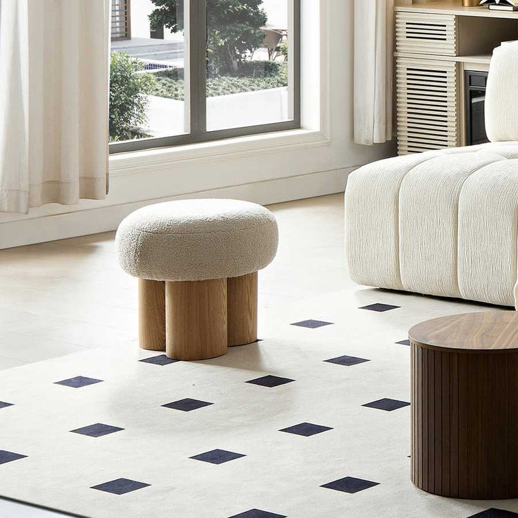 Modern living room with a white ottoman, wooden coffee table, and a window with white curtains.