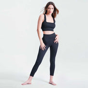 Woman wearing a black athletic outfit on a light gray background