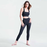 Woman wearing a black athletic outfit on a light gray background