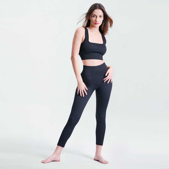 Woman wearing a black athletic outfit on a light gray background