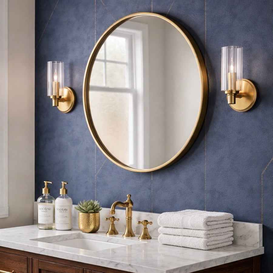 Bathroom with round gold mirror, sink, and towels on a blue tiled wall.