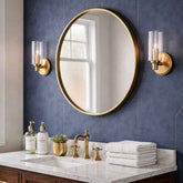 Bathroom with round gold mirror, sink, and towels on a blue tiled wall.