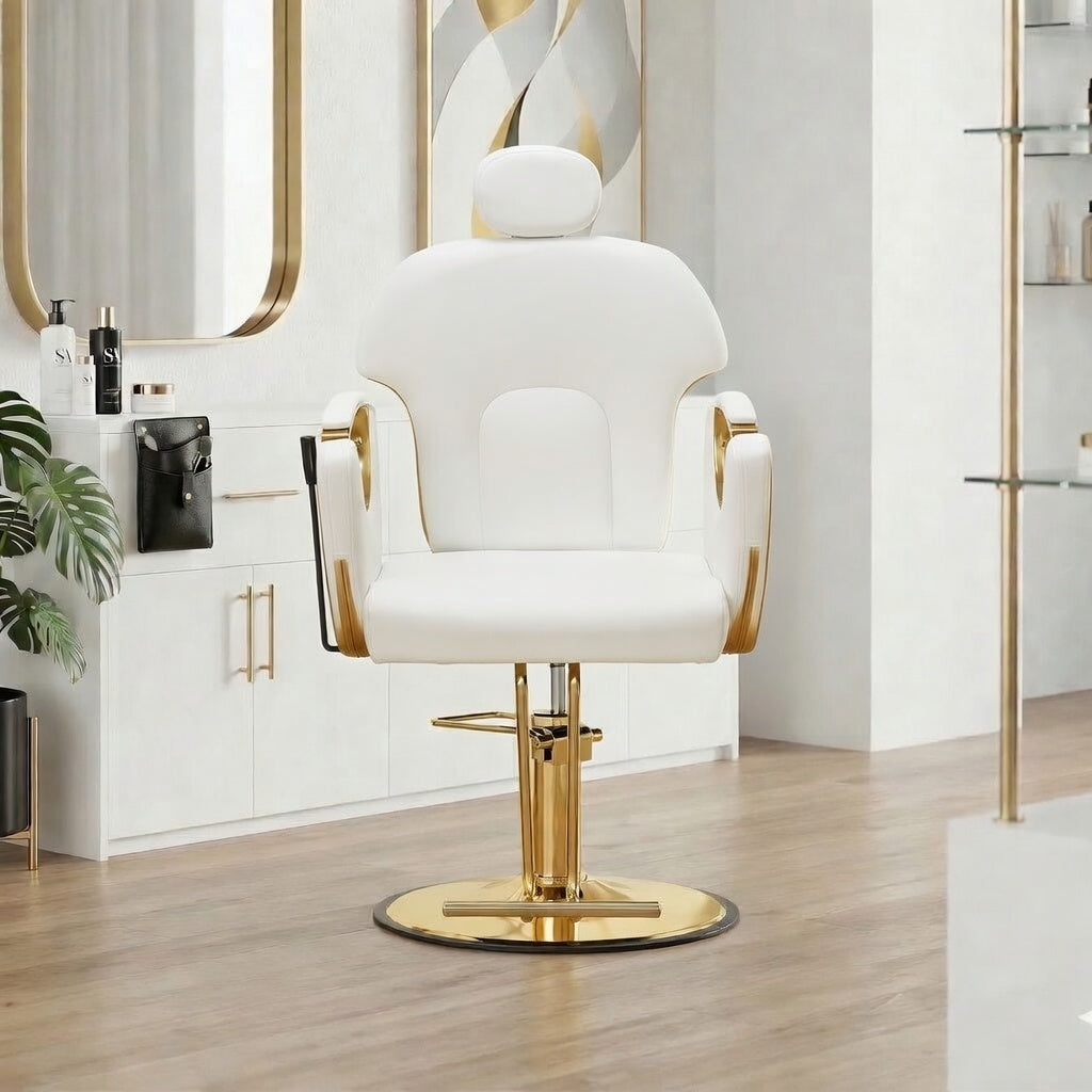 A modern white salon barber chair with gold accents and a gold hydraulic base, set in a bright, contemporary salon interior with light wood floors and white cabinets.