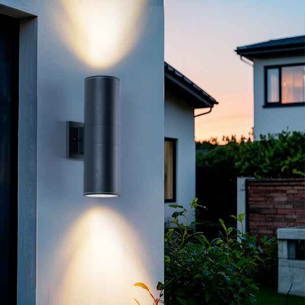 Modern outdoor wall light fixture on a house exterior with a sunset in the background.