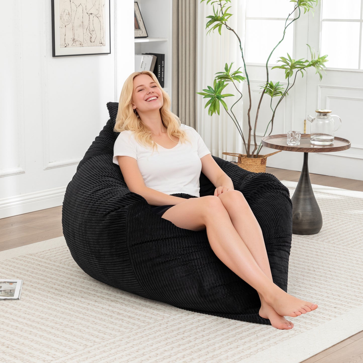 Corduroy Bean Bag Chair - Lounger for Adults & Kids in black, shown in upright position with a woman sitting comfortably in a modern living room.