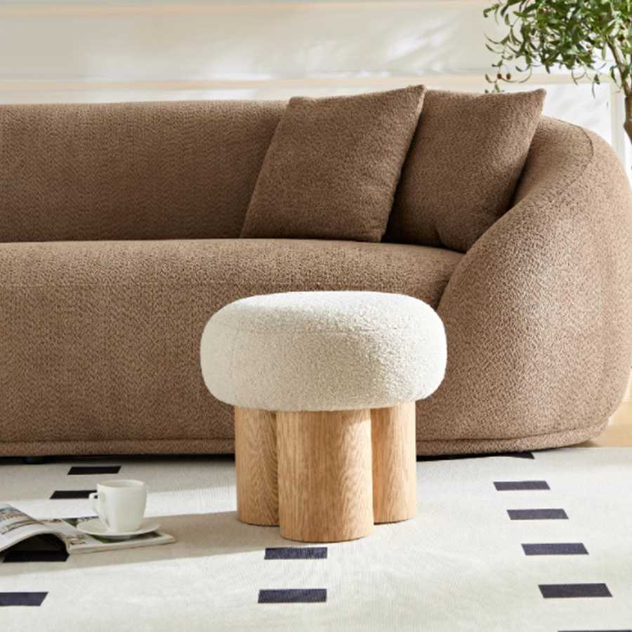 Brown sofa with a white textured ottoman in a living room setting.