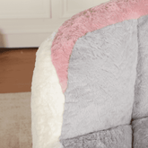 Close-up of a textured blanket with pink, gray, and white sections on a wooden floor.