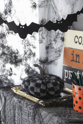 Halloween-themed decor with checkered pumpkin, bats, and spider webs.