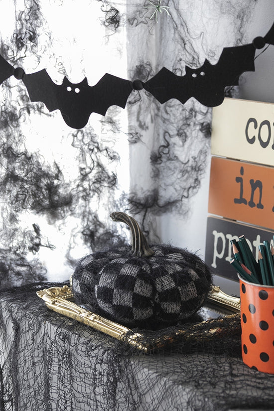 Halloween-themed decor with checkered pumpkin, bats, and spider webs.