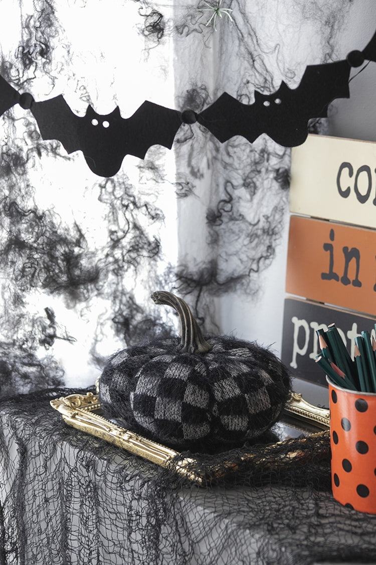 Halloween-themed decor with checkered pumpkin, bats, and spider webs.