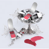 Three Olibolia butterfly-shaped compact makeup palettes in silver with red and pink shades, displayed on a white background with a silver pedestal and lipstick swatches.