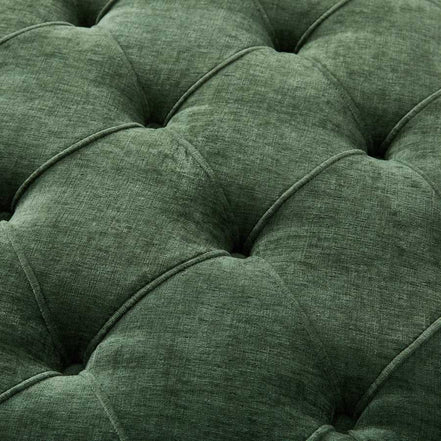 Close-up of a green tufted cushion with a textured fabric surface.