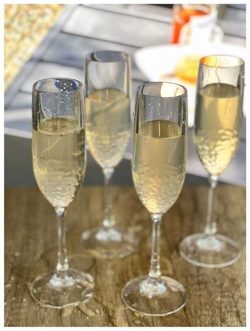 Four unbreakable plastic champagne flutes filled with champagne, ideal for parties and gatherings with a modern touch.