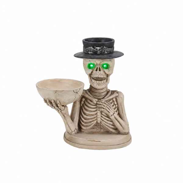 A skeleton figurine wearing a black top hat with bat details and glowing green LED eyes, holding a cracked beige bowl on a white background.