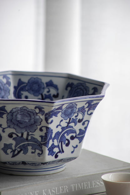 Side view of Blue and White Decorative Bowl - Porcelain, Elegant Design showing floral detailing and curved rim on a book stack.