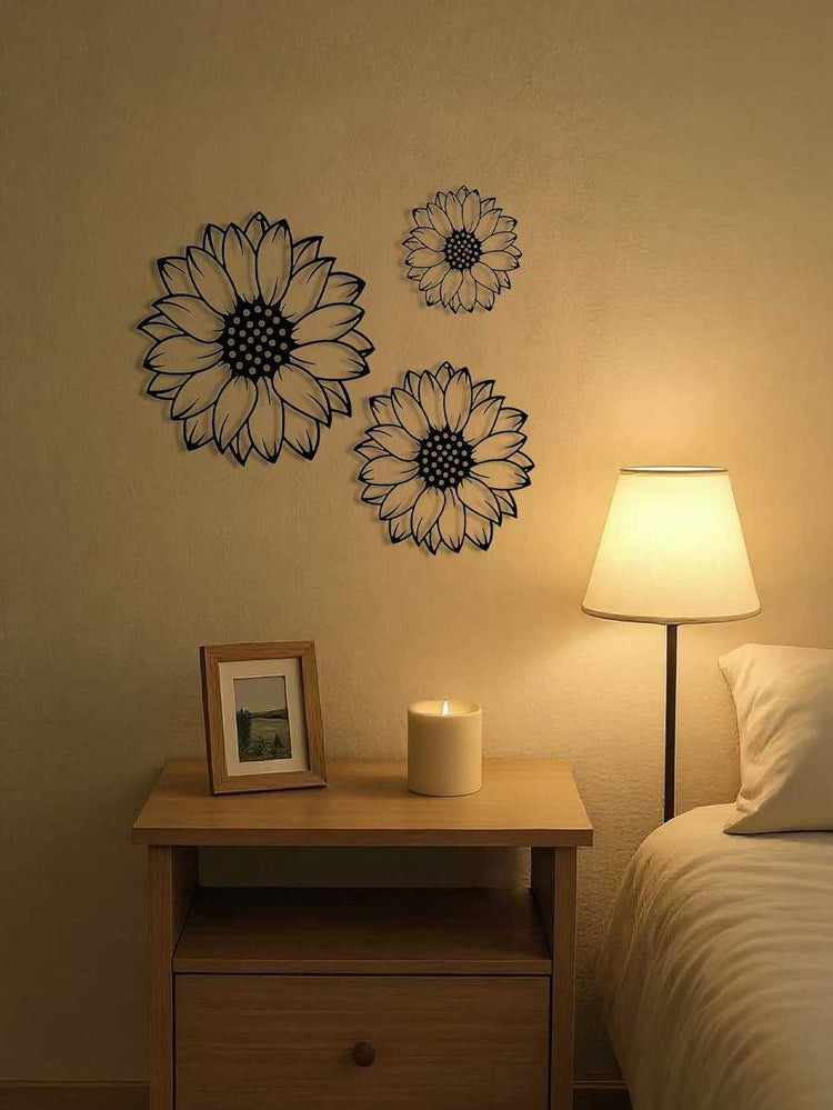 Three-piece elegant metal sunflower wall art set mounted above a nightstand with candle and lamp. Enhances bedroom with rustic floral style.