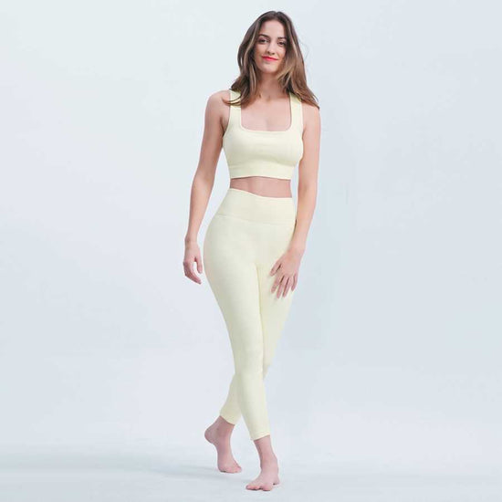 Woman wearing a light yellow athletic outfit on a white background
