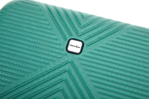 Close-up of a turquoise-green textured suitcase shell with a central square white and black Trapcode logo, showing a geometric chevron pattern.
