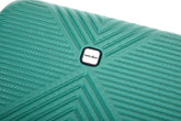 Close-up of a turquoise-green textured suitcase shell with a central square white and black Trapcode logo, showing a geometric chevron pattern.