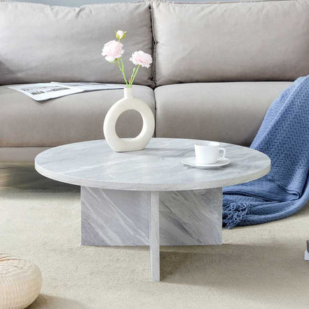 MDF white round coffee table with Nordic flair placed in front of a sofa, showing its modern design and marble-like texture.
