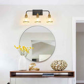 Round mirror on a wooden console table with decorative items and wall lights.