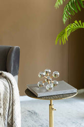 Decorative glass sculpture on a small table with a book underneath, against a neutral wall.