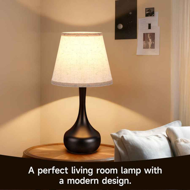 Table lamp with a modern design on a wooden table in a living room setting.