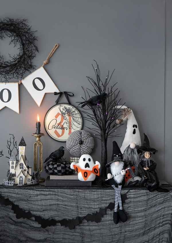 Halloween themed mantel display with October 31 circle sign, spooky decorations, black garland, candles, and Halloween figurines