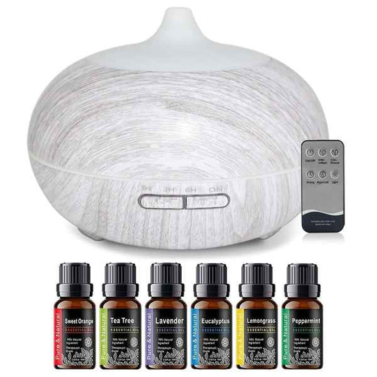 A white wood-grain diffuser with a matching remote control, shown above six essential oil bottles labeled Sweet Orange, Tea Tree, Lavender, Eucalyptus, Lemongrass, and Peppermint.