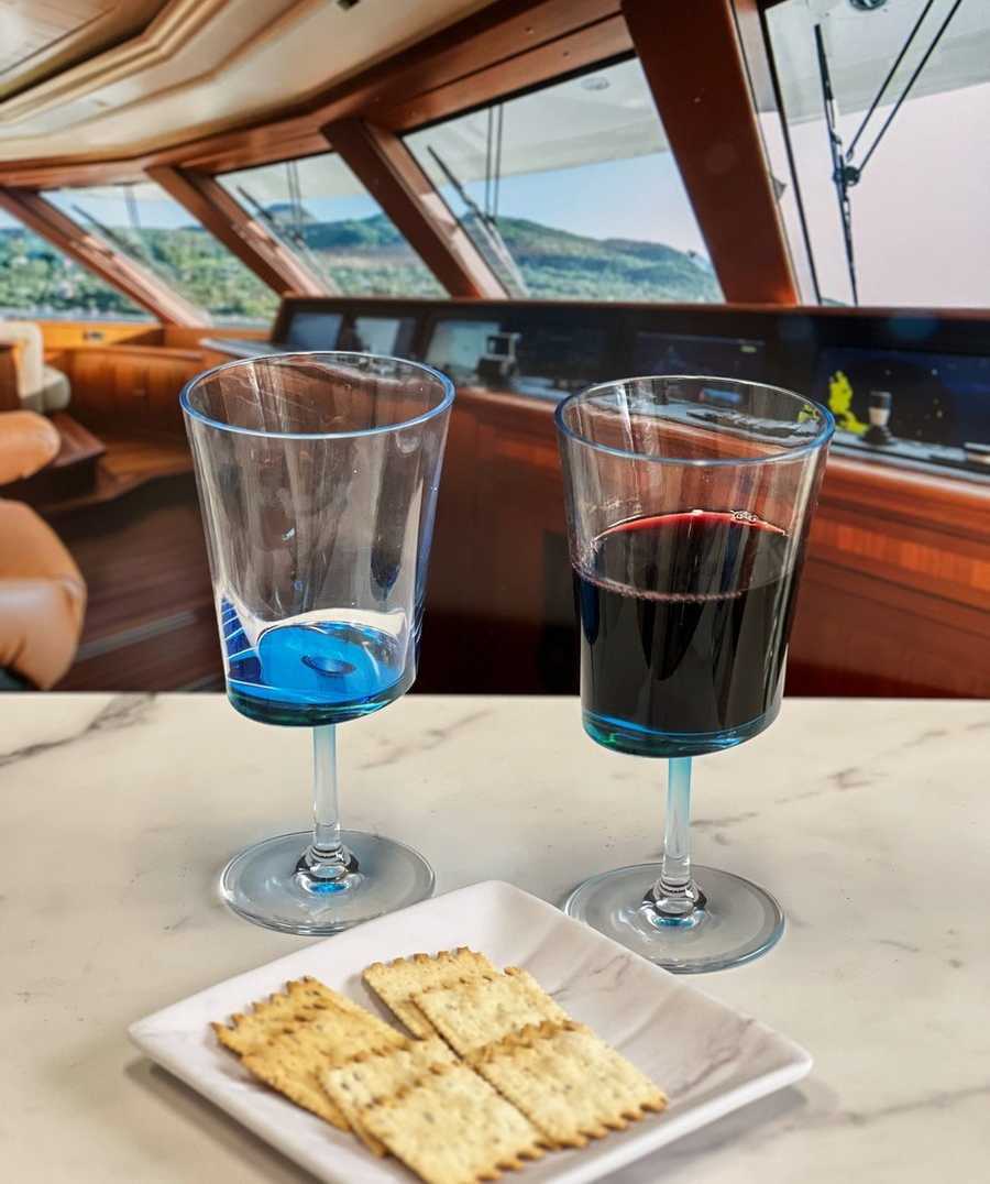 LeadingWare unbreakable wine glasses set of 4 in blue acrylic, displayed on a yacht table with red wine and crackers for stylish entertaining.