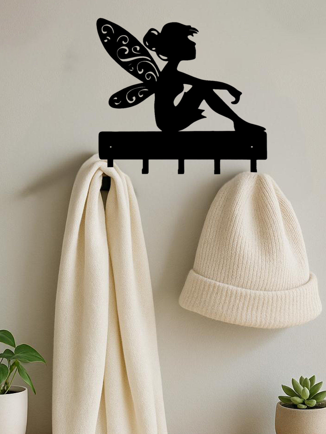 Fantasy wall hook key holder with fairy silhouette design, mounted on a beige wall holding a hat and scarf. Ideal wall decor for entryways.