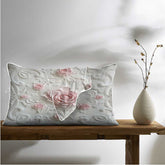 Decorative pillow with floral design on a wooden table next to a vase.
