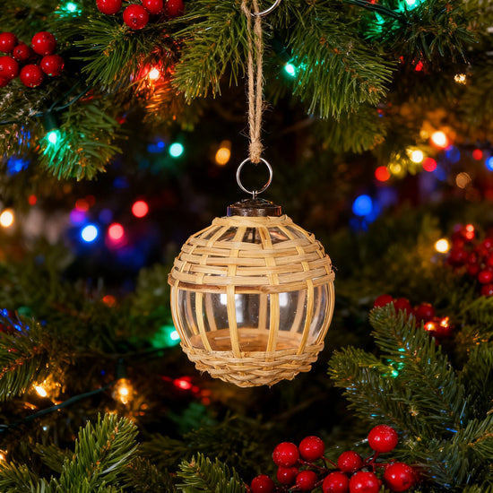 Woven Christmas ornament hanging on a decorated tree with colorful lights in the background