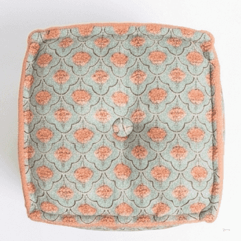 A square floor cushion or pouf with a muted sage green background and a repeating coral-orange floral pattern, finished with a solid coral-orange piped edge.