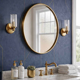 Bathroom with round gold mirror, gold fixtures, and blue tiled wall.