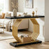 A modern console table with a black marble-look top and base, and a geometric gold metal frame, styled in a bright living room next to a beige sofa.