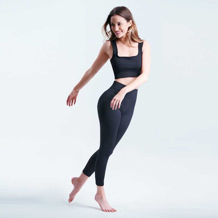 Woman wearing a black athletic outfit on a light gray background
